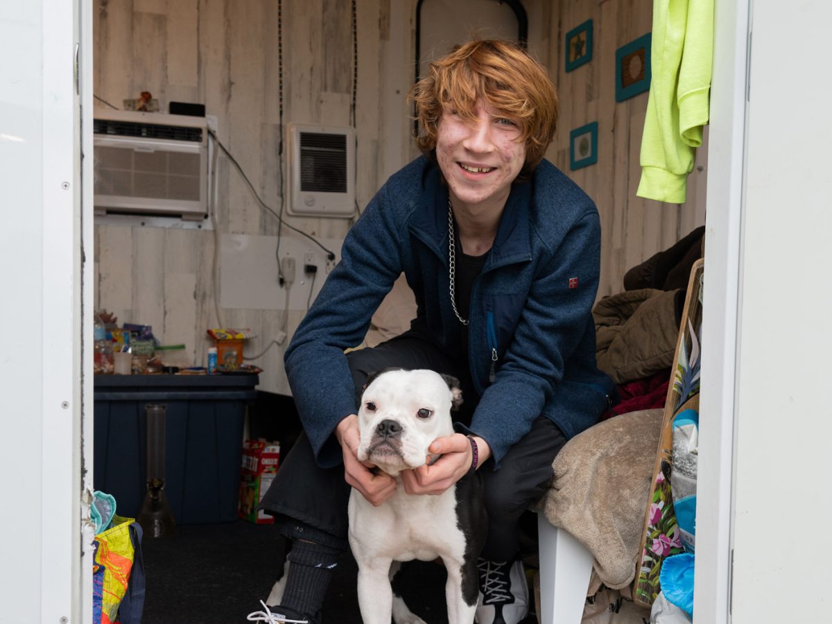 Man smiling in and Urban Alchemy housed community with their dog.