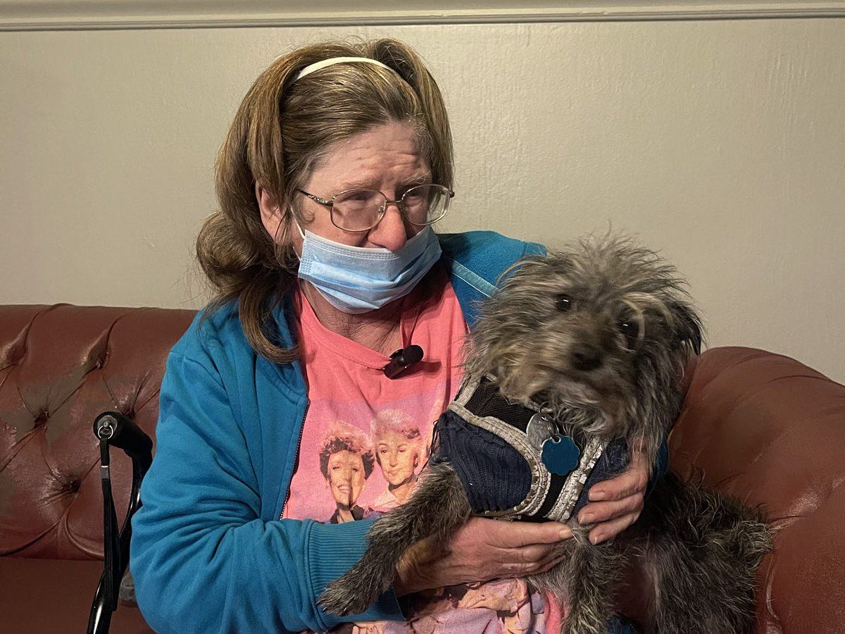 Delcia Carter sitting on a couch with her beloved dog.