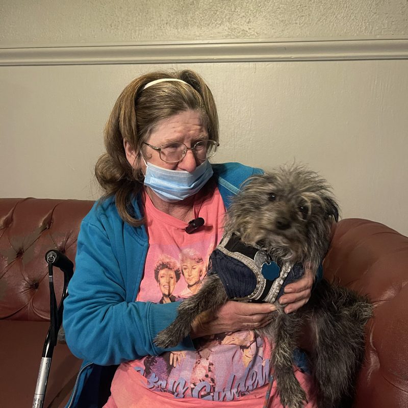 Delcia Carter sitting on a couch with her beloved dog.